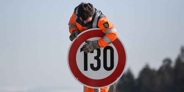 Ein Straßenwärter und ein Tempo-130-Schild Ein Straßenwärter und ein Tempo-130-Schild