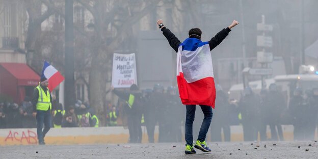 Eine Person hat sich eine französische Flagge umgehängt und reckt die Arme in die Höhe Eine Person hat sich eine französische Flagge umgehängt und reckt die Arme in die Höhe