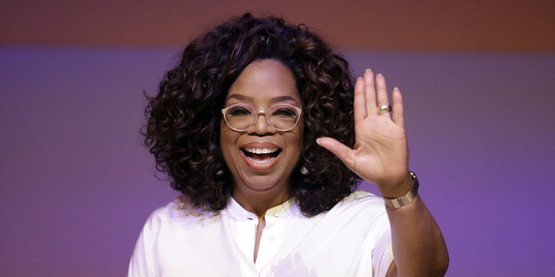 Oprah Winfrey hebt ihre linke Hand nach oben Oprah Winfrey hebt ihre linke Hand nach oben