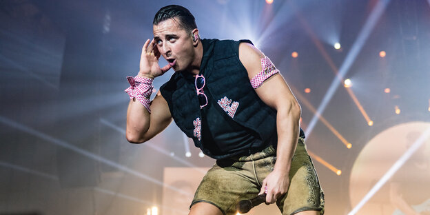 Andreas Gabalier trägt eine Lederhose und hält sich eine Hand an sein Ohr Andreas Gabalier trägt eine Lederhose und hält sich eine Hand an sein Ohr