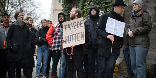 Eine Gruppe Menschen steht mit Protestschildern vor einem Haus