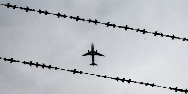 Vor einem Stacheldraht ist ein Flugzeug zu sehen