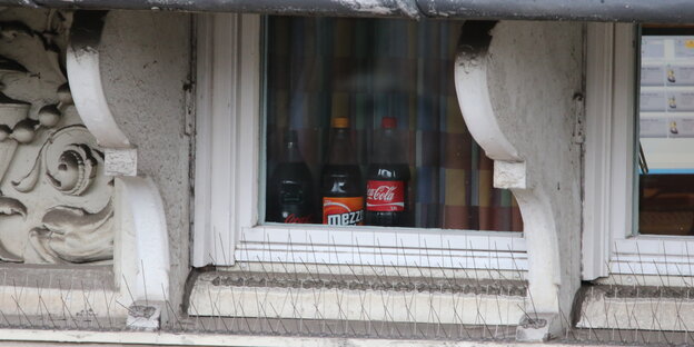 Drei Flaschen stehen hinter einem Fenster. In der linken ist eine Kamera zu erkennen Drei Flaschen stehen hinter einem Fenster. In der linken ist eine Kamera zu erkennen