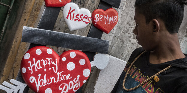 Ein Junge betrachtet zum Valentinstag aufgehängte Herzen Ein Junge betrachtet zum Valentinstag aufgehängte Herzen