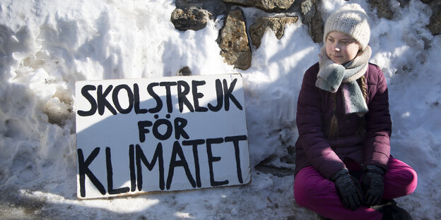 mädchen mit Mütze und Schild "Schulstreik fürs Klima" im Schnee mädchen mit Mütze und Schild "Schulstreik fürs Klima" im Schnee