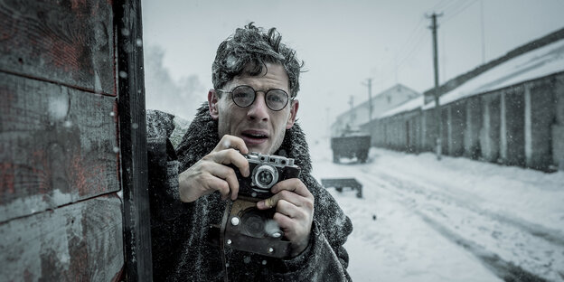 Ein Reporter mit Brille macht Fotos an einem verschneiten Bahnhof Ein Reporter mit Brille macht Fotos an einem verschneiten Bahnhof