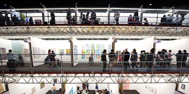 Menschen stehen in einer Halle auf Galerien Menschen stehen in einer Halle auf Galerien