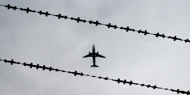 Ein Flugzeug, fotografiert durch einen Stacheldrahtzaun. Ein Flugzeug, fotografiert durch einen Stacheldrahtzaun.