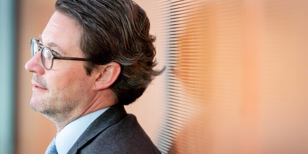 Ein Mann mit Brille lehnt an eine Wand und guckt in die Ferne. Ein Mann mit Brille lehnt an eine Wand und guckt in die Ferne.