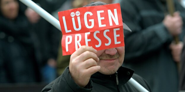 Ein Mann hält eine Karte mit der Aufschrift "Lügenpresse" hoch Ein Mann hält eine Karte mit der Aufschrift "Lügenpresse" hoch