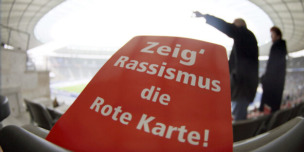 Eine rote Karte mit der Aufschrift "Zeig Rassismus die Rote Karte" liegt auf einem der Zuschauerplätze im Berliner Olympiastadion. Eine rote Karte mit der Aufschrift "Zeig Rassismus die Rote Karte" liegt auf einem der Zuschauerplätze im Berliner Olympiastadion.