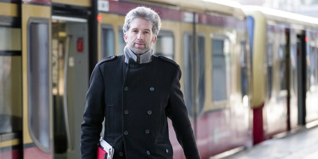 Ein Mantel tragender Mann mit kurzen Haaren und Drei-Tage-Bart steigt aus der Berliner S-Bahn Ein Mantel tragender Mann mit kurzen Haaren und Drei-Tage-Bart steigt aus der Berliner S-Bahn