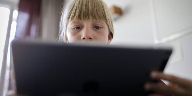 mädchen sitzt an einem tablet und spielt oder arbeitet damit mädchen sitzt an einem tablet und spielt oder arbeitet damit