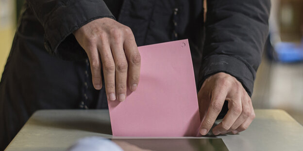 Ein Mensch wirft einen Wahlzettel in eine Wahlurne Ein Mensch wirft einen Wahlzettel in eine Wahlurne