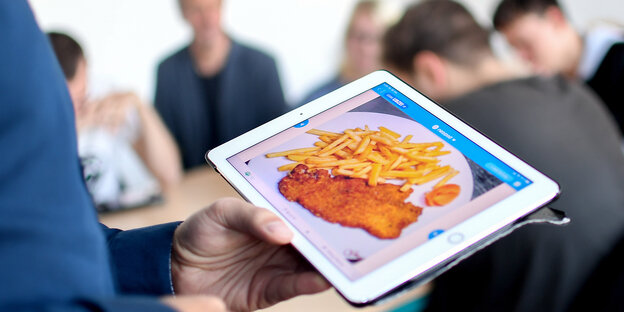 Berliner Schüler schaut sich auf einem Tablet ein Schnitzel-Pommes-Gericht an Berliner Schüler schaut sich auf einem Tablet ein Schnitzel-Pommes-Gericht an
