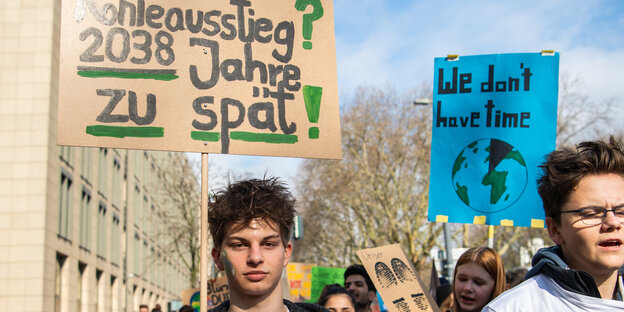 Ein Schüler hält auf einer Demo ein Plakat hoch