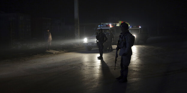 Polizisten sperren die Straße in der Nähe eines Autobomben-Anschlags in Kabul Polizisten sperren die Straße in der Nähe eines Autobomben-Anschlags in Kabul