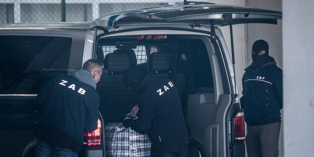 Drei Männer stehen am Kofferraum eines Transporters Drei Männer stehen am Kofferraum eines Transporters