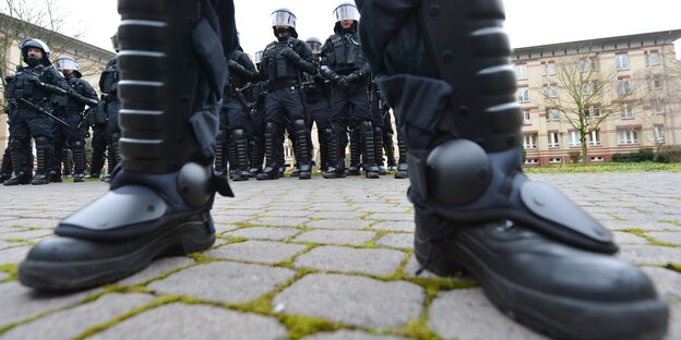 Nahaufnahme von Polizeistiefeln, dahinter einige PolizistInnen in Sicherheitsmontur Nahaufnahme von Polizeistiefeln, dahinter einige PolizistInnen in Sicherheitsmontur