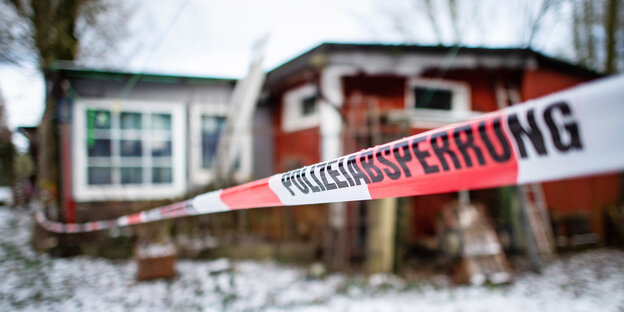 absperrband mit dem schriftzug "Polizeiabsperrung" vor der holzhütte des hauptverdächtigen im schnee absperrband mit dem schriftzug "Polizeiabsperrung" vor der holzhütte des hauptverdächtigen im schnee