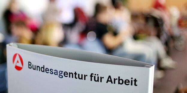 Ein Schild mit der Aufschrift «Bundesagentur für Arbeit» steht einem vollen Wartezimmer im Jobcenter. Ein Schild mit der Aufschrift «Bundesagentur für Arbeit» steht einem vollen Wartezimmer im Jobcenter.