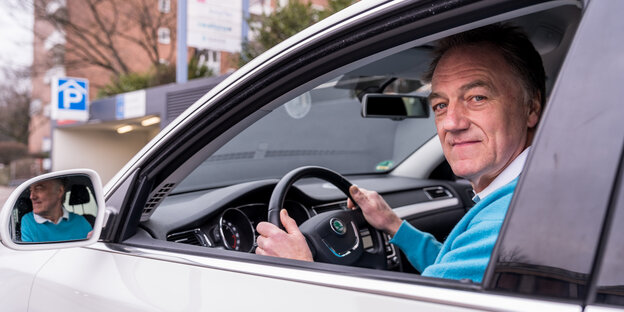 Ein Mann schaut aus der Seitenscheibe seines Autos Ein Mann schaut aus der Seitenscheibe seines Autos