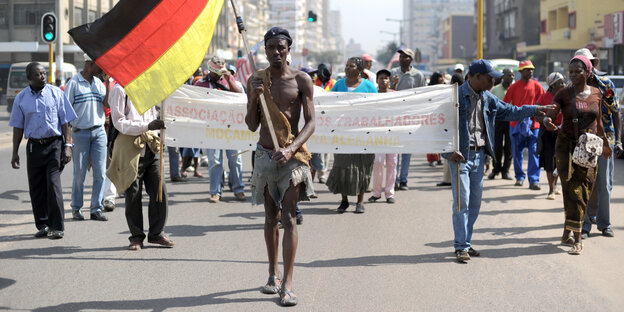 Eine Demo in Mosambik, voraus läuft ein Demonstrant, der eine Deutschlandfahne trägt Eine Demo in Mosambik, voraus läuft ein Demonstrant, der eine Deutschlandfahne trägt