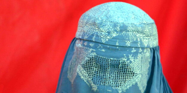 eine Frau unter einer blauen Burka vor totem Hintergrund eine Frau unter einer blauen Burka vor totem Hintergrund