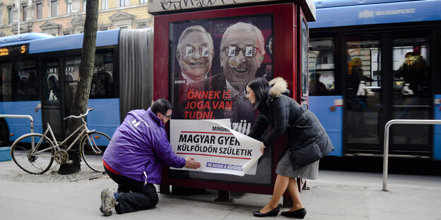 Zwei Mitglieder der proeuropäischen Bewegung "Momentum" überkleben ein Hetzplakat mit Informationen gegen Viktor Orbáns Politik Zwei Mitglieder der proeuropäischen Bewegung "Momentum" überkleben ein Hetzplakat mit Informationen gegen Viktor Orbáns Politik