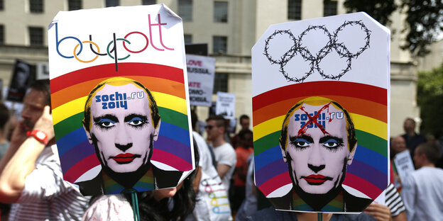 Menschen halten Plakate mit einem künstlerisch verfremdeten Gesicht Wladimir Putins in die Höhe Menschen halten Plakate mit einem künstlerisch verfremdeten Gesicht Wladimir Putins in die Höhe