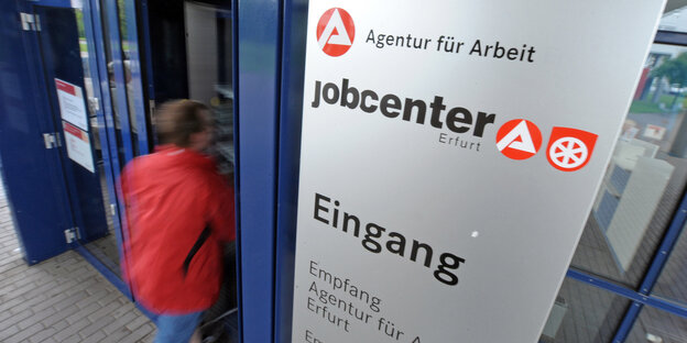 Ein Mensch geht durch den Eingang eines Jobcenters Ein Mensch geht durch den Eingang eines Jobcenters