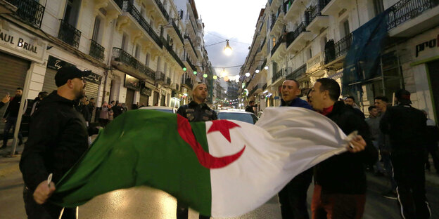 Algerier halten ihre Nationalflagge, während sie in den Straßen von Algier feiern Algerier halten ihre Nationalflagge, während sie in den Straßen von Algier feiern