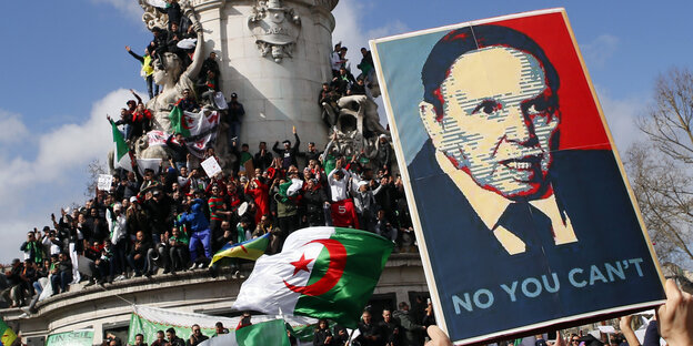 Hunderte Demonstranten klettern auf ein Gebäude, viele tragen algerische Fahnen, ein Schild mit dem Konterfei von Abdelaziz Bouteflika und der Aufschrif "No you can't" wird nach oben gehalten Hunderte Demonstranten klettern auf ein Gebäude, viele tragen algerische Fahnen, ein Schild mit dem Konterfei von Abdelaziz Bouteflika und der Aufschrif "No you can't" wird nach oben gehalten