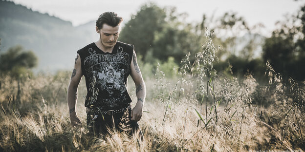 Ein Junger Mann mit bedrucktem T-Shirt in einer Wiese Ein Junger Mann mit bedrucktem T-Shirt in einer Wiese