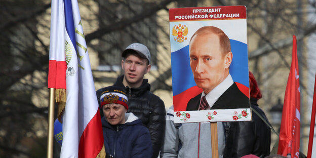 Bei der Feier zur Annektierung der Krim trägt ein Mann ein Plakat mit einem Foto von Putin Bei der Feier zur Annektierung der Krim trägt ein Mann ein Plakat mit einem Foto von Putin