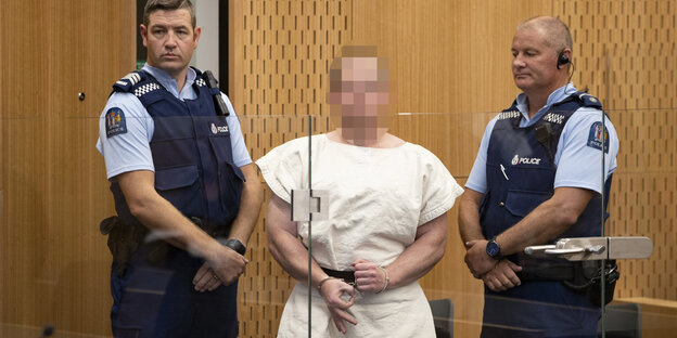 Ein Mann mit unkenntlich gemachtem Gesicht zwischen zwei Polizisten Ein Mann mit unkenntlich gemachtem Gesicht zwischen zwei Polizisten