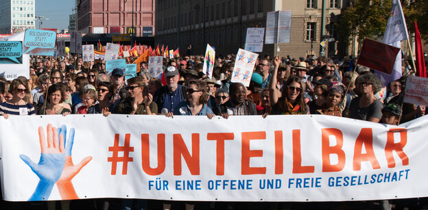 Eine Menschenmenge trägt ein Transparent mit der Aufschrift "#unteilbar" Eine Menschenmenge trägt ein Transparent mit der Aufschrift "#unteilbar"