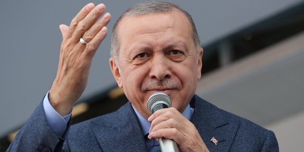 Erdoğan spricht mit erhobener Hand in ein Mikrofon. Erdoğan spricht mit erhobener Hand in ein Mikrofon.