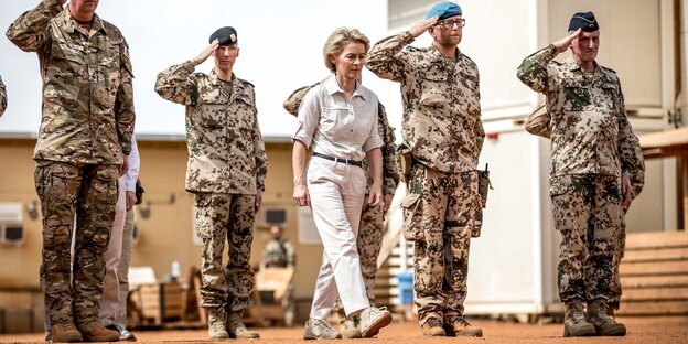 Ursula von der Leyen steht zwischen salutierenden uniformierten Soldaten Ursula von der Leyen steht zwischen salutierenden uniformierten Soldaten
