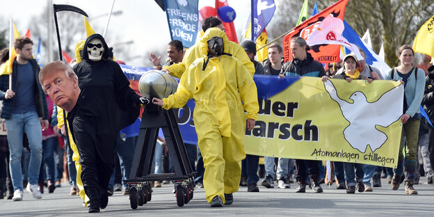 Menschen sind teilweise verkleidet und gehen gemeinsam mit Transparenten und Plakaten auf die Kamera zu Menschen sind teilweise verkleidet und gehen gemeinsam mit Transparenten und Plakaten auf die Kamera zu