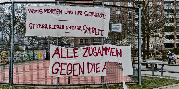 An einem Sportplatz-Zaun hängt ein Plakat mit der Aufschrift "Nazis morden und ihr schweigt - Sticker kleben und ihr schreit". An einem Sportplatz-Zaun hängt ein Plakat mit der Aufschrift "Nazis morden und ihr schweigt - Sticker kleben und ihr schreit".