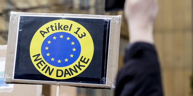 Auf einem Schild ist ein gelber Kreis zu sehen, der eine blaue Fläche mit den europäischen Sternen umschließt. In der geleben Fläche steht: Artikel 13, Nein Danke Auf einem Schild ist ein gelber Kreis zu sehen, der eine blaue Fläche mit den europäischen Sternen umschließt. In der geleben Fläche steht: Artikel 13, Nein Danke