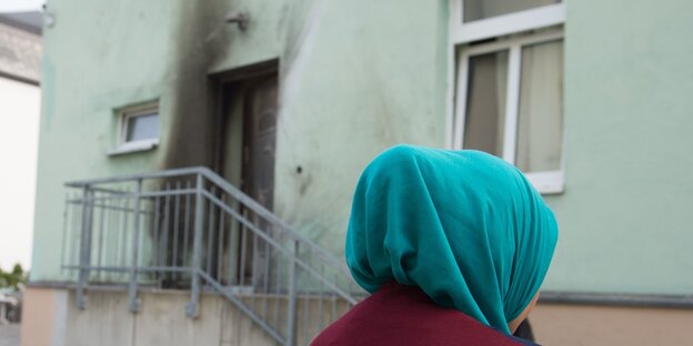 Eine Frau vor einem verkokelten Eingang Eine Frau vor einem verkokelten Eingang