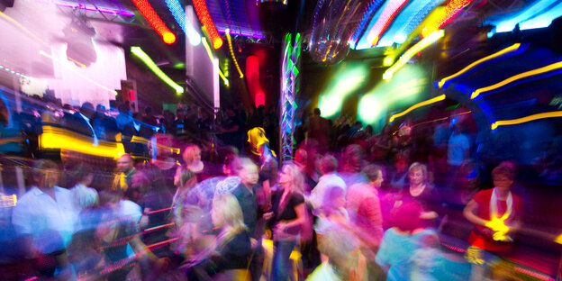 Auf einer Tanzfläche stehen Menschen, viele bunte Lichter leuchten Auf einer Tanzfläche stehen Menschen, viele bunte Lichter leuchten