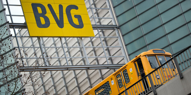 Eine U-Bahn fährt untern einem Schild her auf dem BVG steht Eine U-Bahn fährt untern einem Schild her auf dem BVG steht