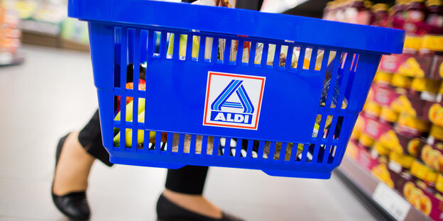 Eine Frau steht vor einem Supermarktregal und hält einen Einkaufskorb des Discounters Aldi Nord. Eine Frau steht vor einem Supermarktregal und hält einen Einkaufskorb des Discounters Aldi Nord.