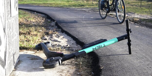 Ein E-Scooter liegt auf der Straße und ein Radfahrer weicht aus Ein E-Scooter liegt auf der Straße und ein Radfahrer weicht aus