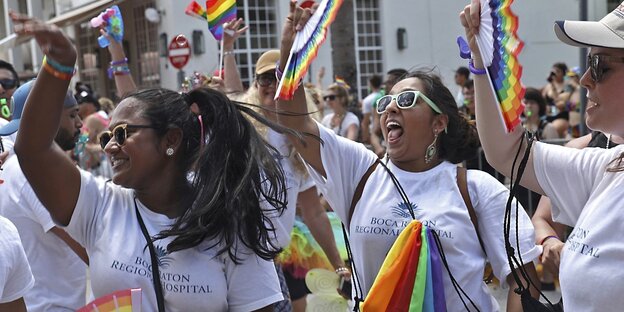 Eine Gruppe von Frauen tanzt mit bunten LGBTQI-Flaggen und -Fächern Eine Gruppe von Frauen tanzt mit bunten LGBTQI-Flaggen und -Fächern