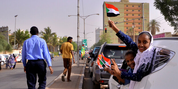 Menschen halten sudanesische Fahnen aus einem Auto Menschen halten sudanesische Fahnen aus einem Auto