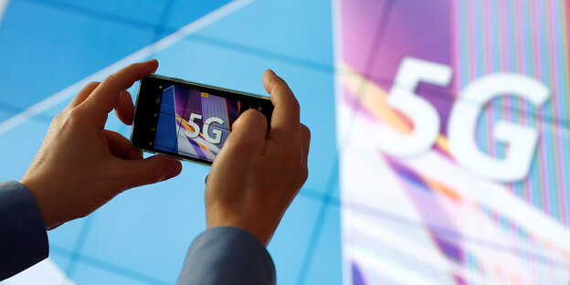 Jemand fotografiert mit einem Smartphone einen Bildschirm, auf dem 5G steht Jemand fotografiert mit einem Smartphone einen Bildschirm, auf dem 5G steht